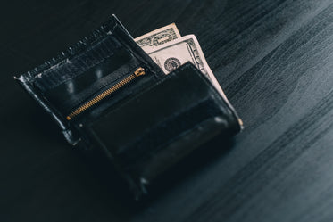 black wallet with money on a grey wood grain surface