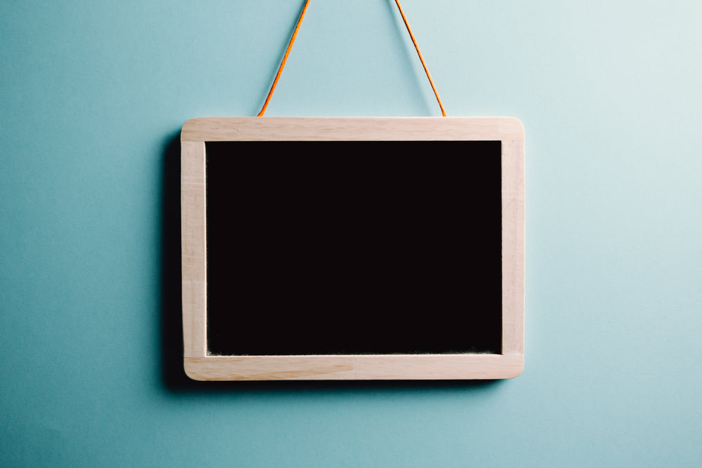 blank wood frame chalkboard hangs on a blue wall