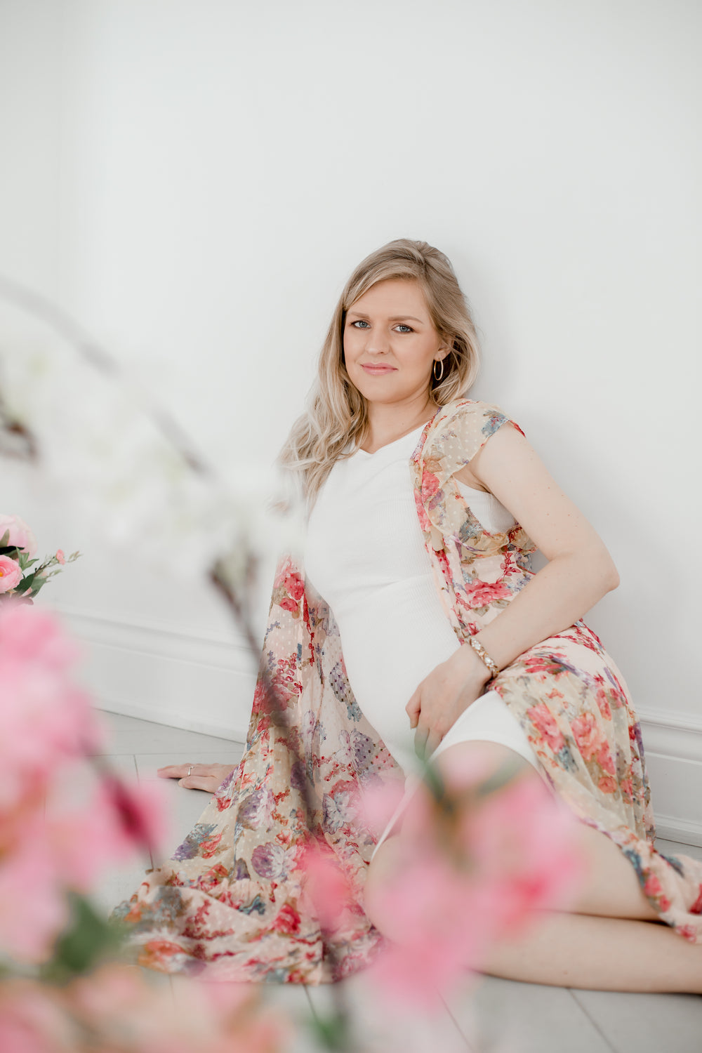 blond woman in a white dress sits on the floor