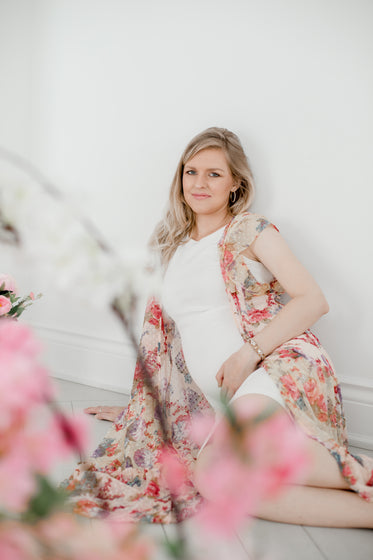 blond woman in a white dress sits on the floor