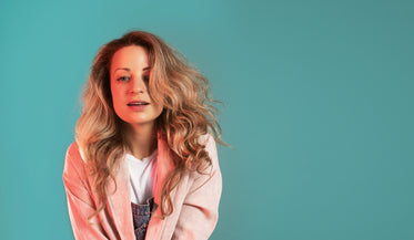 blonde woman caught mid-smile against turquoise wall