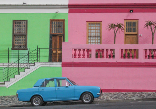 blue car parked next to a green and pink building