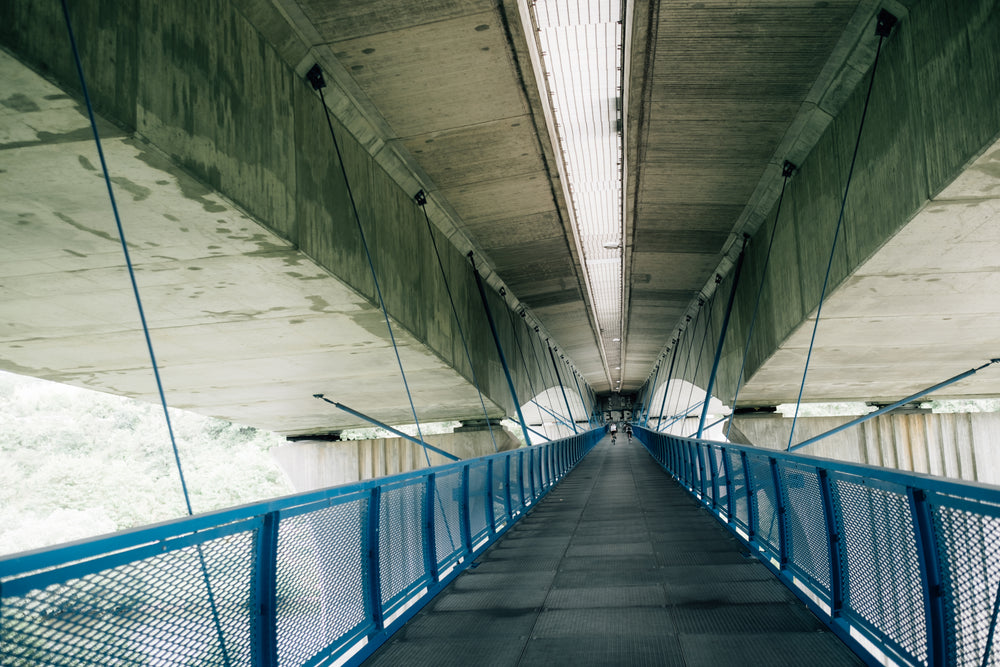 blue metal walkway attached to the concrete ceiling with wire