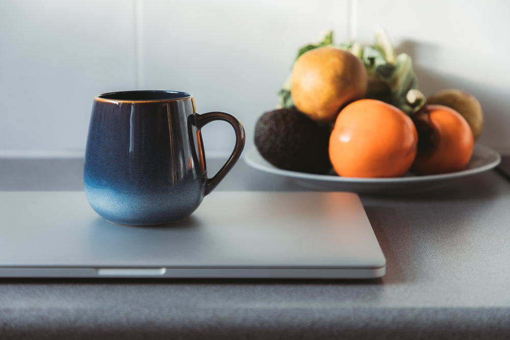 blue mug and laptop sit on a kitchen counter