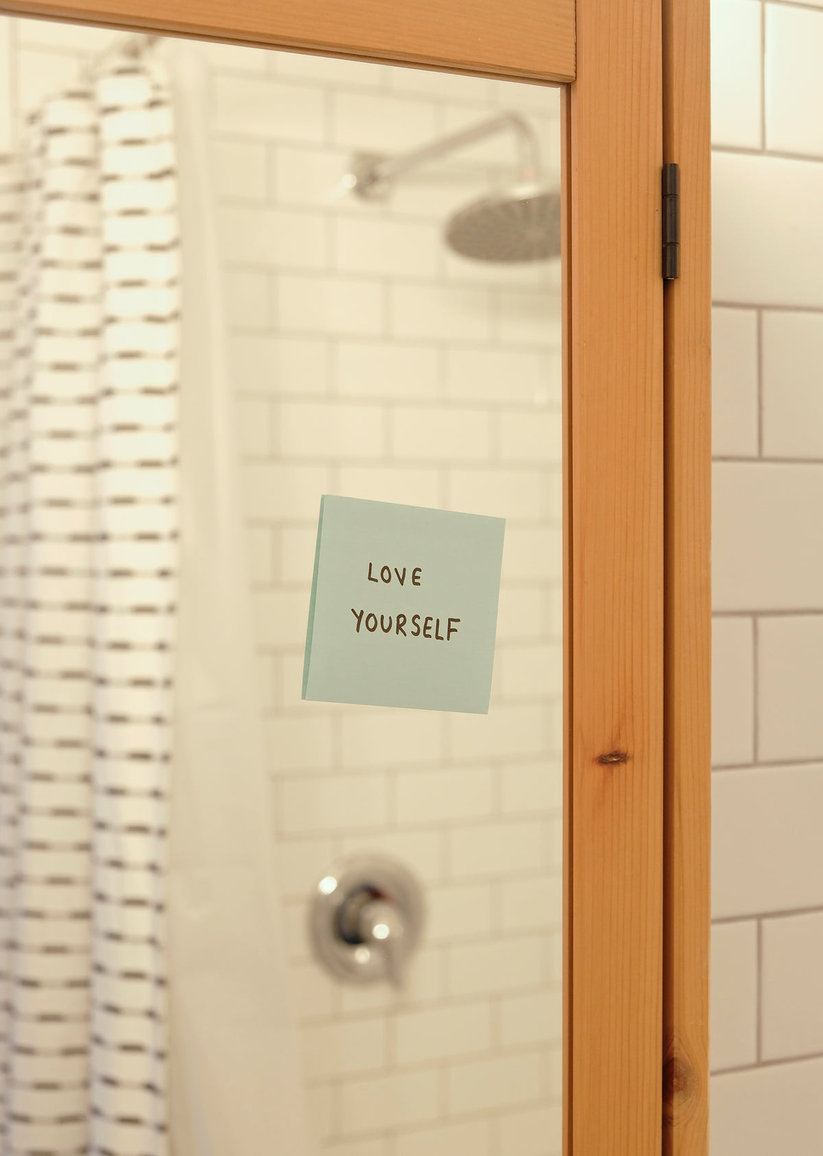 blue note on a bathroom mirror reads love yourself