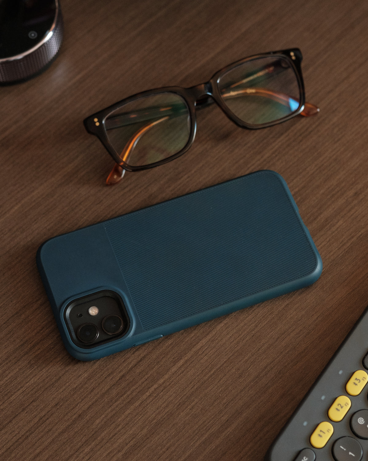 蓝色手机壳和眼镜放在木桌上