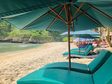 blue sun shades and deck chairs on a golden sandy beach