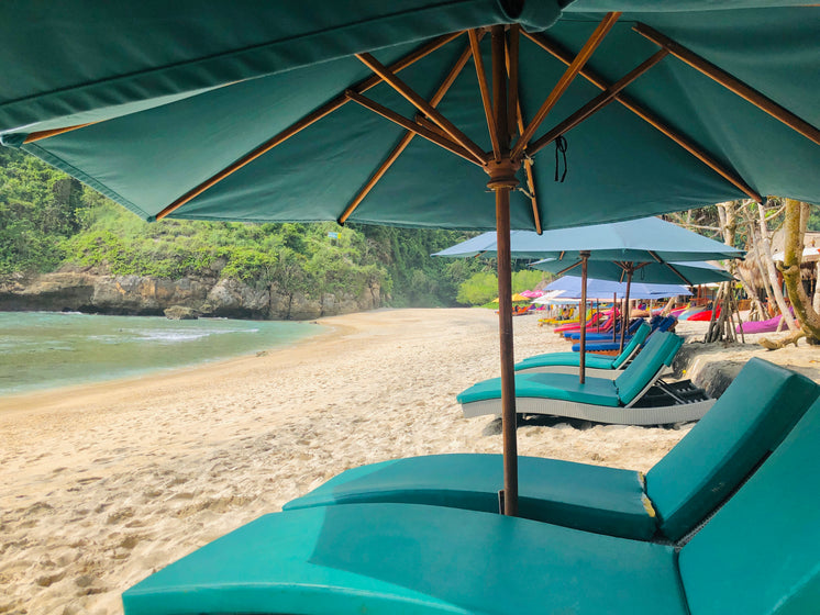 Blue Sun Shades And Deck Chairs On A Golden Sandy Beach