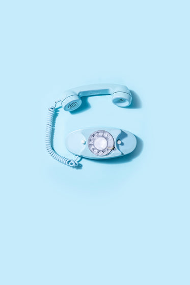 blue vintage rotary telephone laid on blue background