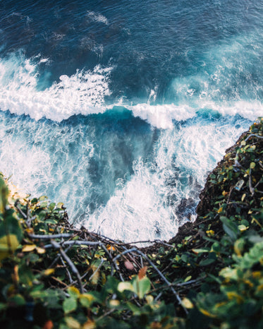 blue waves crash at base of cliff