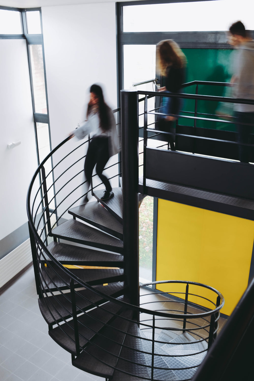 blurred students rush down spiral stairs