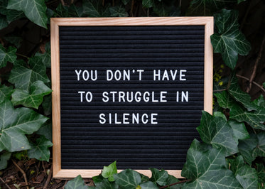 board with a message lays surrounded by english ivy