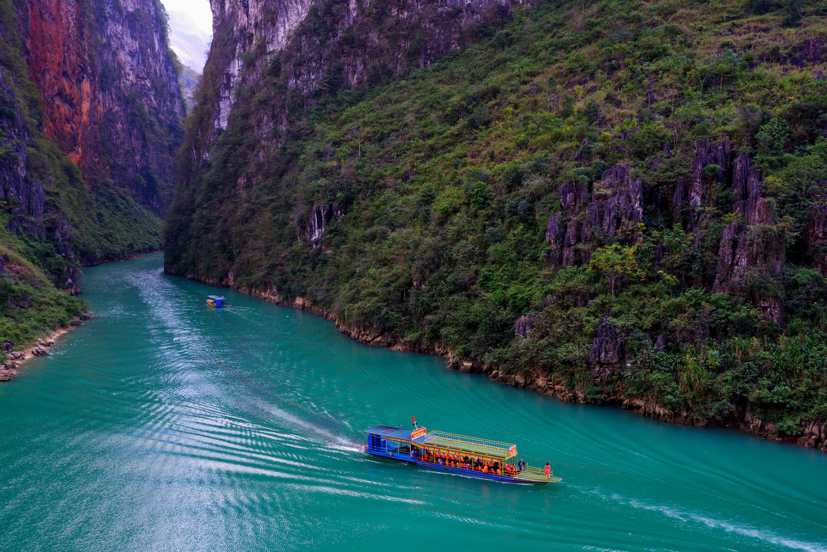 boat travels along river between luscious green mountains