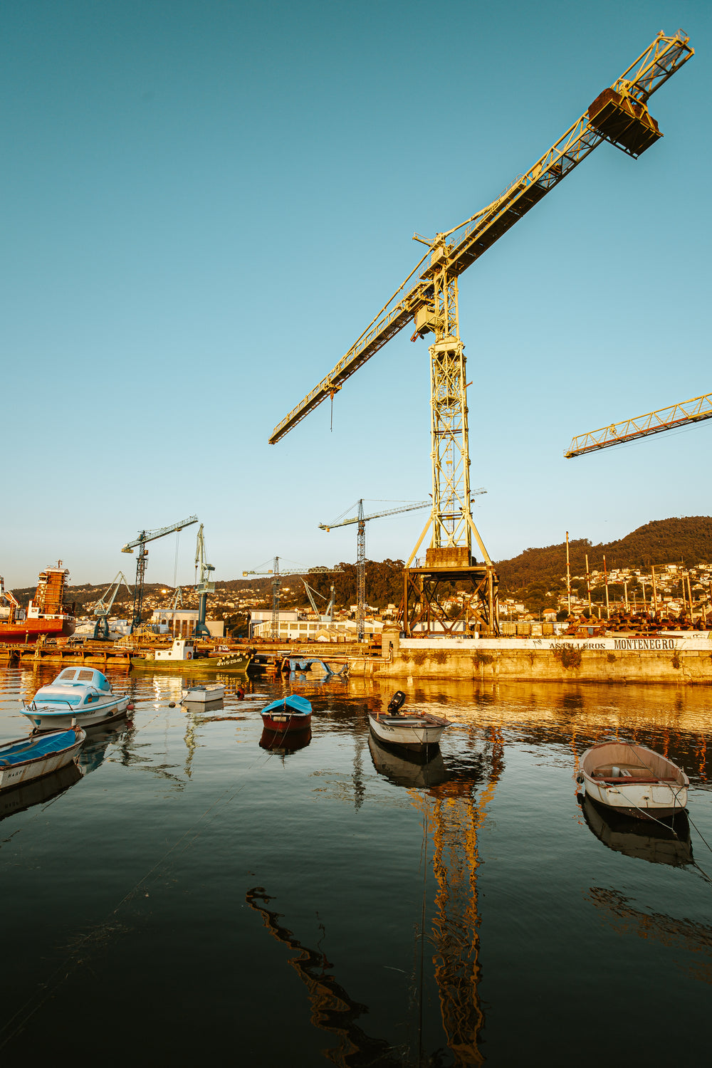 boats and cranes lit by a rising sun