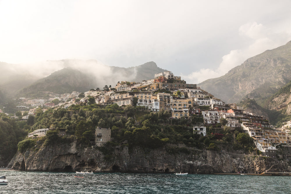 boats sailing under buildings on rock face