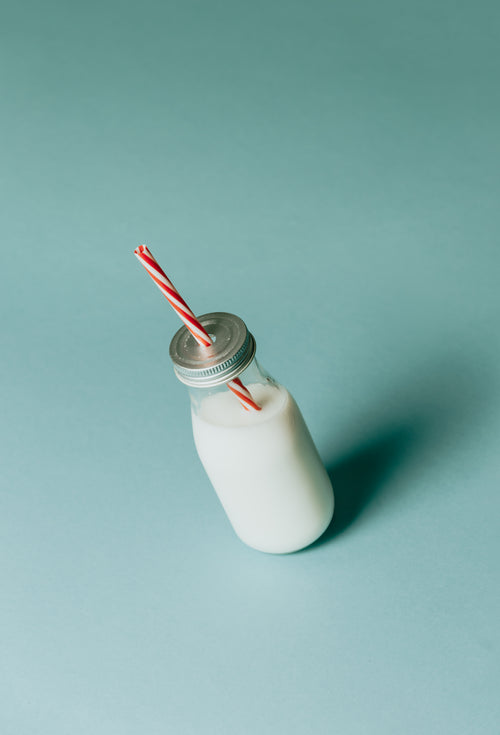 bottle of milk with silver lid and red striped straw
