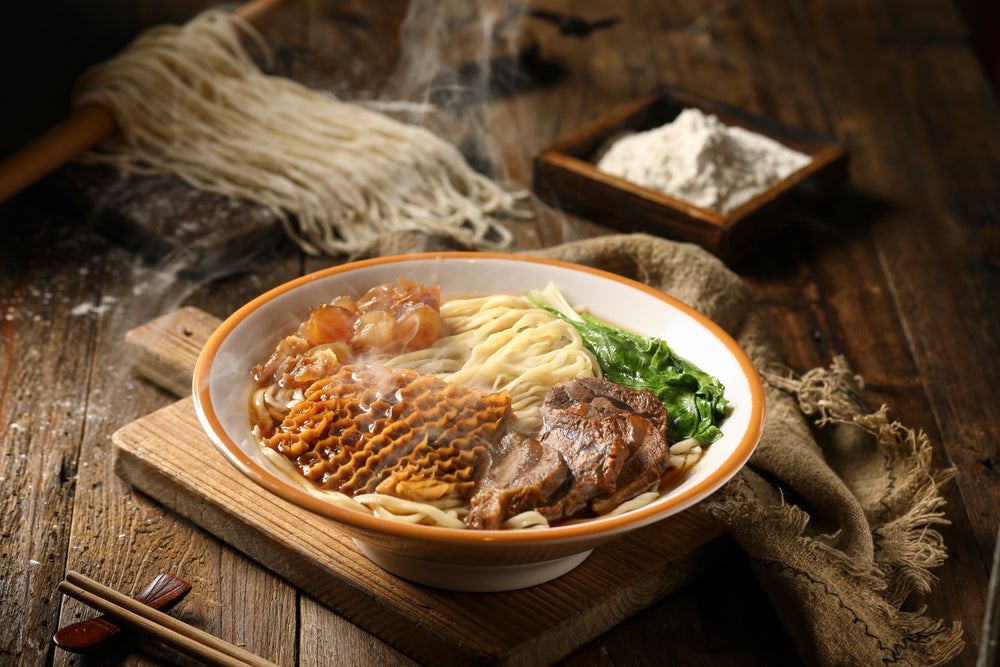 Bowl Of Noodle Soup With More Ingredients Behind