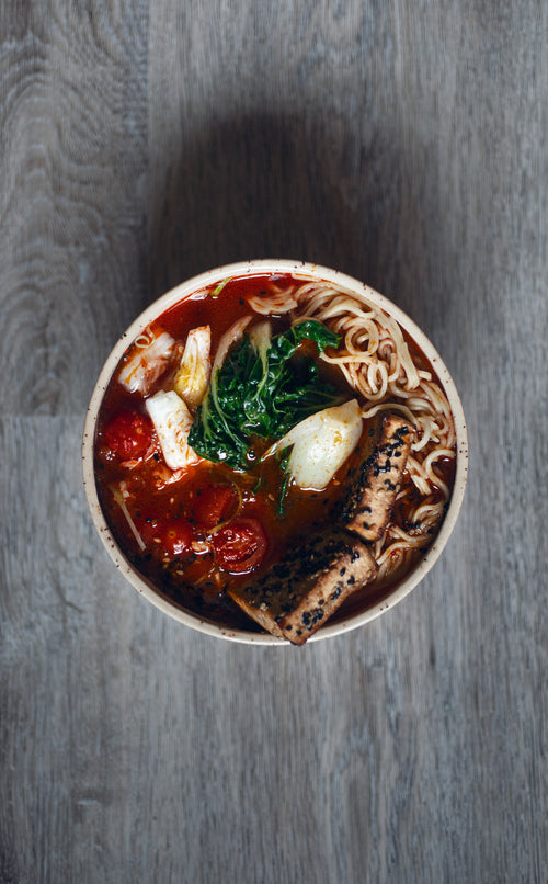 bowl of red noodle soup on a wooden surface
