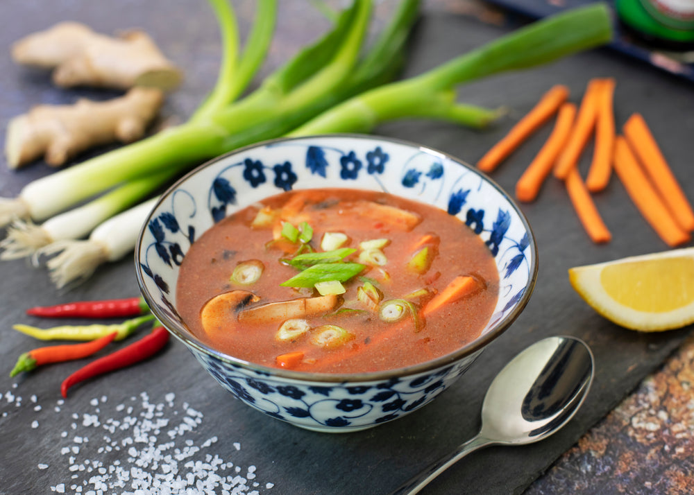 bowl of soup on table surrounded by vegetables