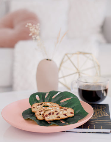 breakfast biscotti lays on a monstera leaf on a pink plate