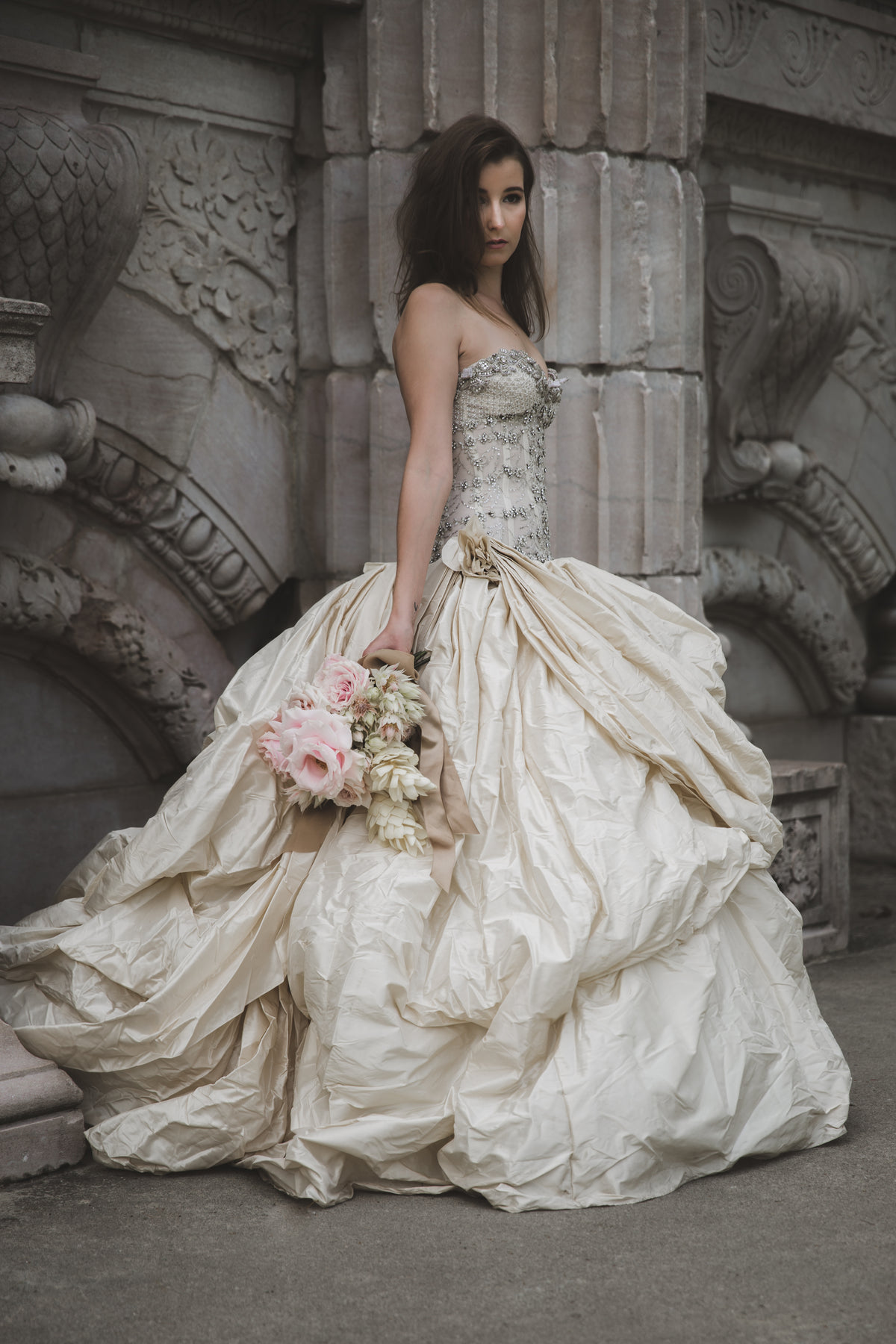 bride holding bouquet in front of old wall vertical