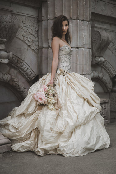 bride holding bouquet in front of old wall vertical