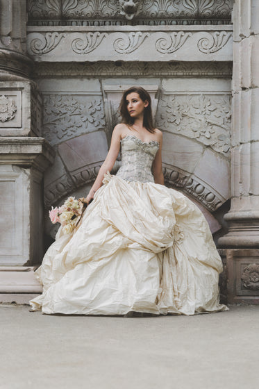 bride holding flowers in front of old wall vertical