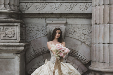 bride holding flowers in front of old wall