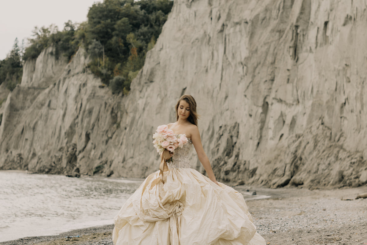 身着婚纱的新娘站在悬崖和海滩旁