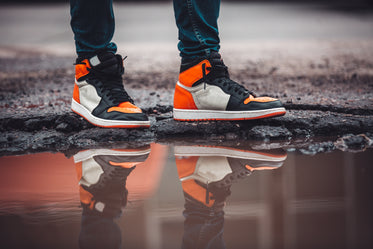 bright fashion sneakers reflect in puddle on asphalt street