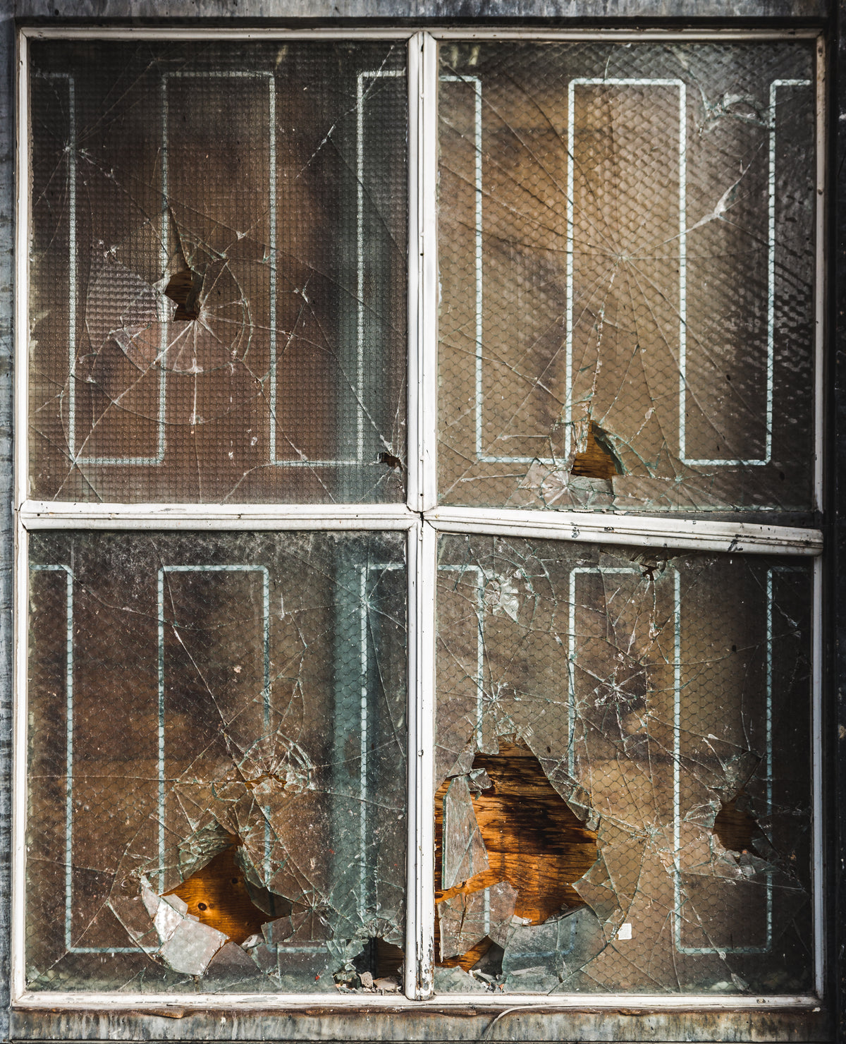 broken shards of glass hanging in a boarded up window