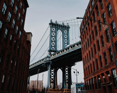 brooklyn bridge towers over brick buildings in williamsburg