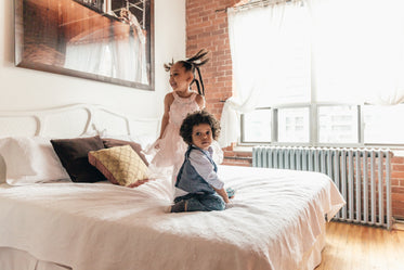 brother and sister playing on bed