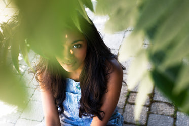 brown eyed girl peeks through leaves