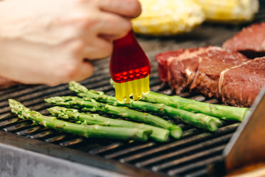brushing cooking oil on bbq asparagus
