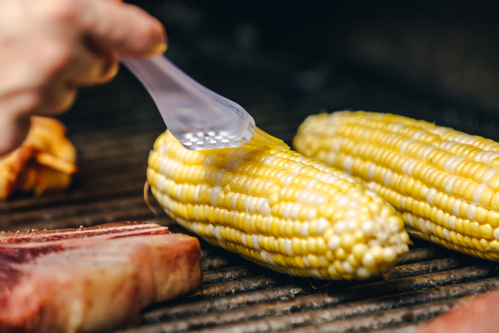 brushing cooking oil on bbq corn