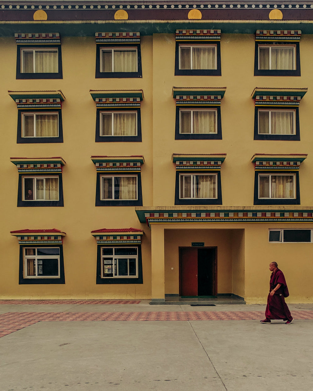 buddhist monk walks by yellow building