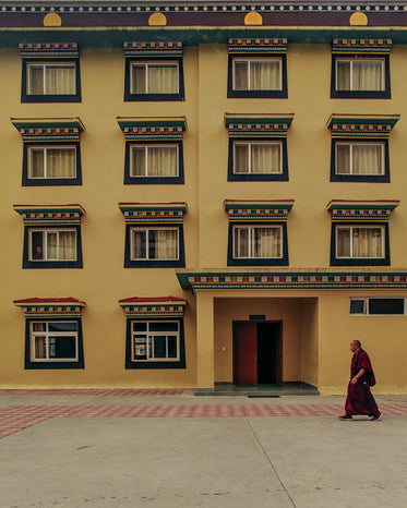 buddhist monk walks by yellow building