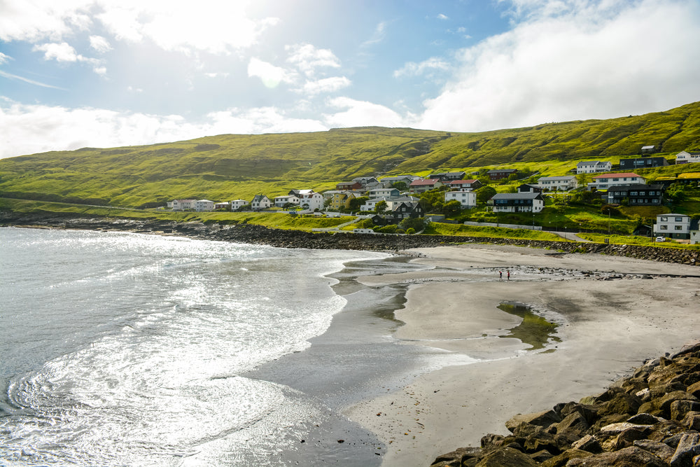 buildings of the city of sandavagur along a calm sandy beach