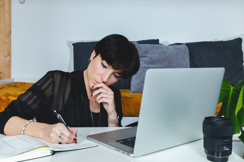 business woman sits in front of an open laptop and notebook