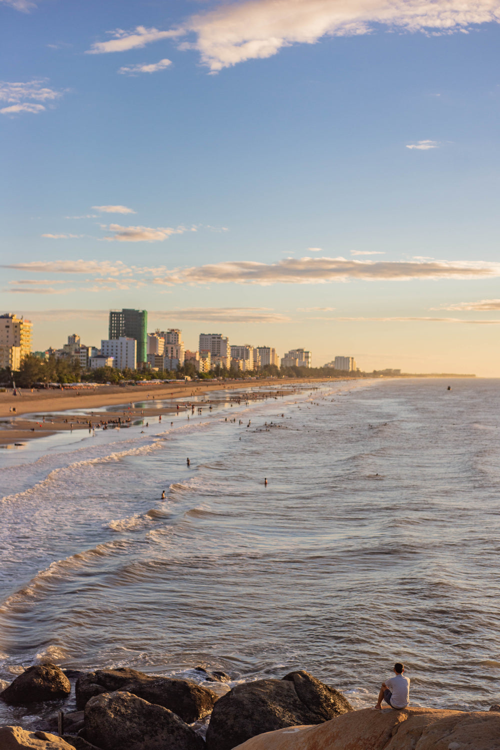 busy beach with city buildings surrounding the coastline