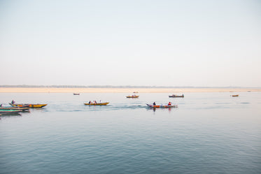 calm water with people rowing multiple thin boats
