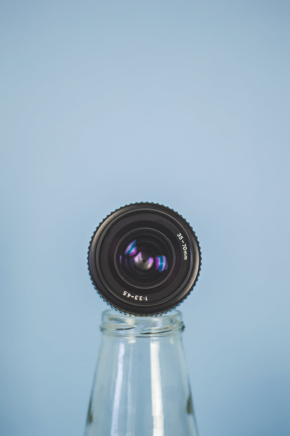 camera lens propped on a bottle