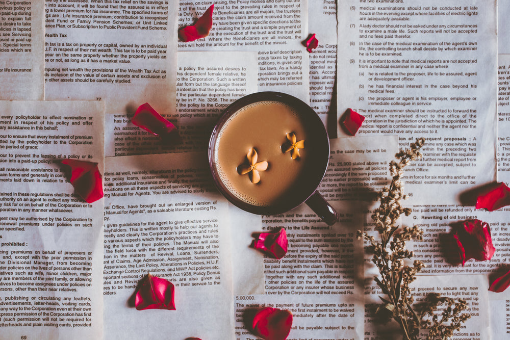 camera looks down at a mug with petals scattered around it