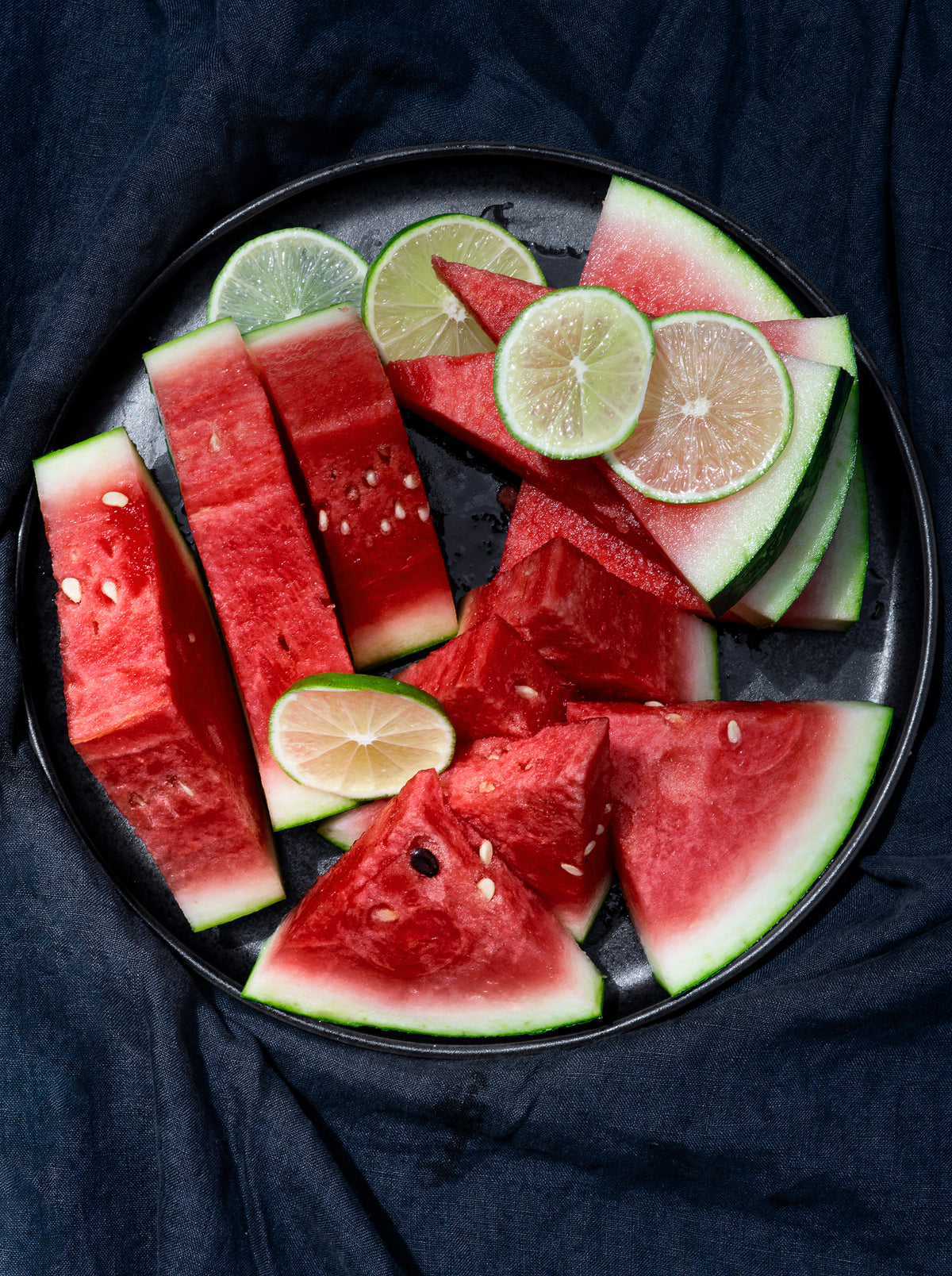 camera looks down at a plate of watermelon and lime