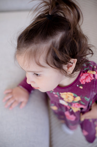 camera looks down at a toddler dressed in pink floral sweater