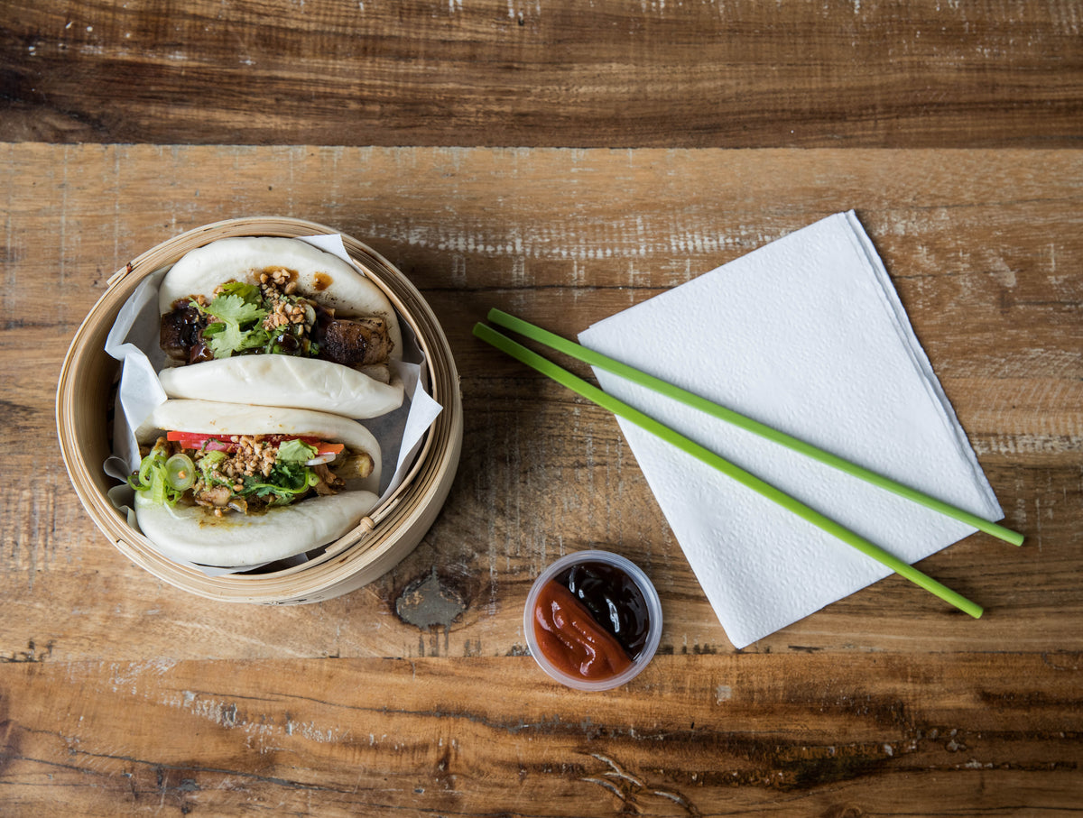 camera looks down on wooden table with two bao buns