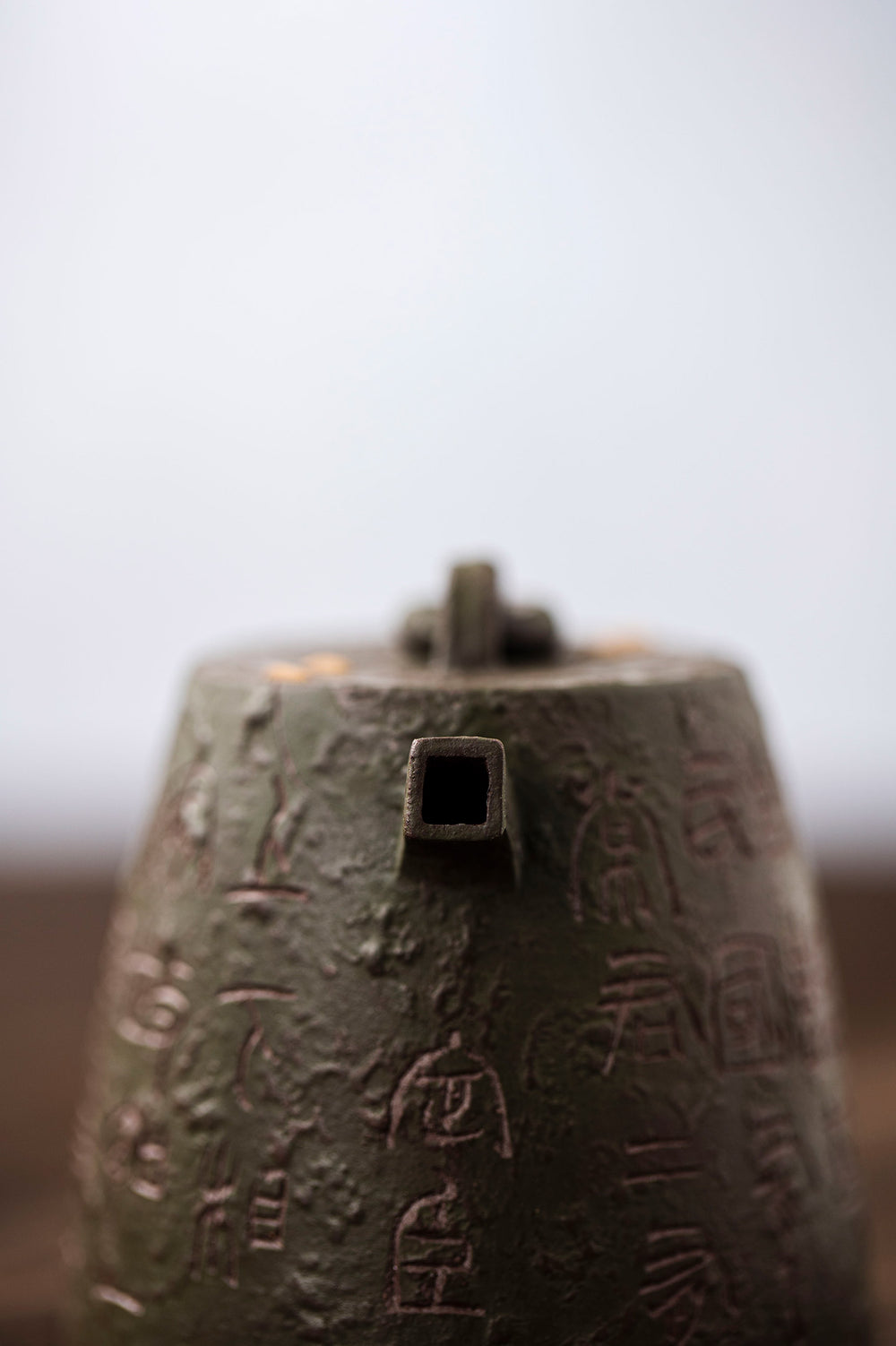 camera looks down the spout of a metal teapot