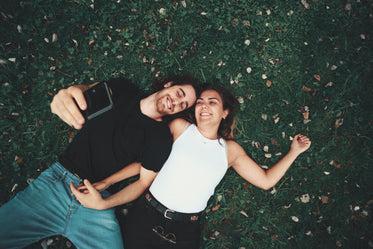 camera looks down towards a couple laying on green grass