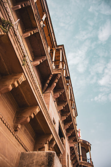 camera looks up to a rust colored building